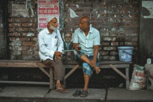 ベンチに座って話す男性2人の写真